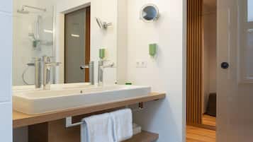Een moderne badkamer met een grote spiegel, een wastafel en een douche.
