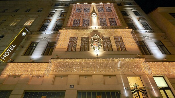 La façade d’un hôtel, avec une grande entrée, des détails architecturaux travaillés et une enseigne indiquant le nom de l’hôtel.