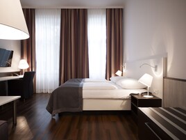 Een moderne hotelkamer met een bed, nachtkastjes, een bureau en een televisie.