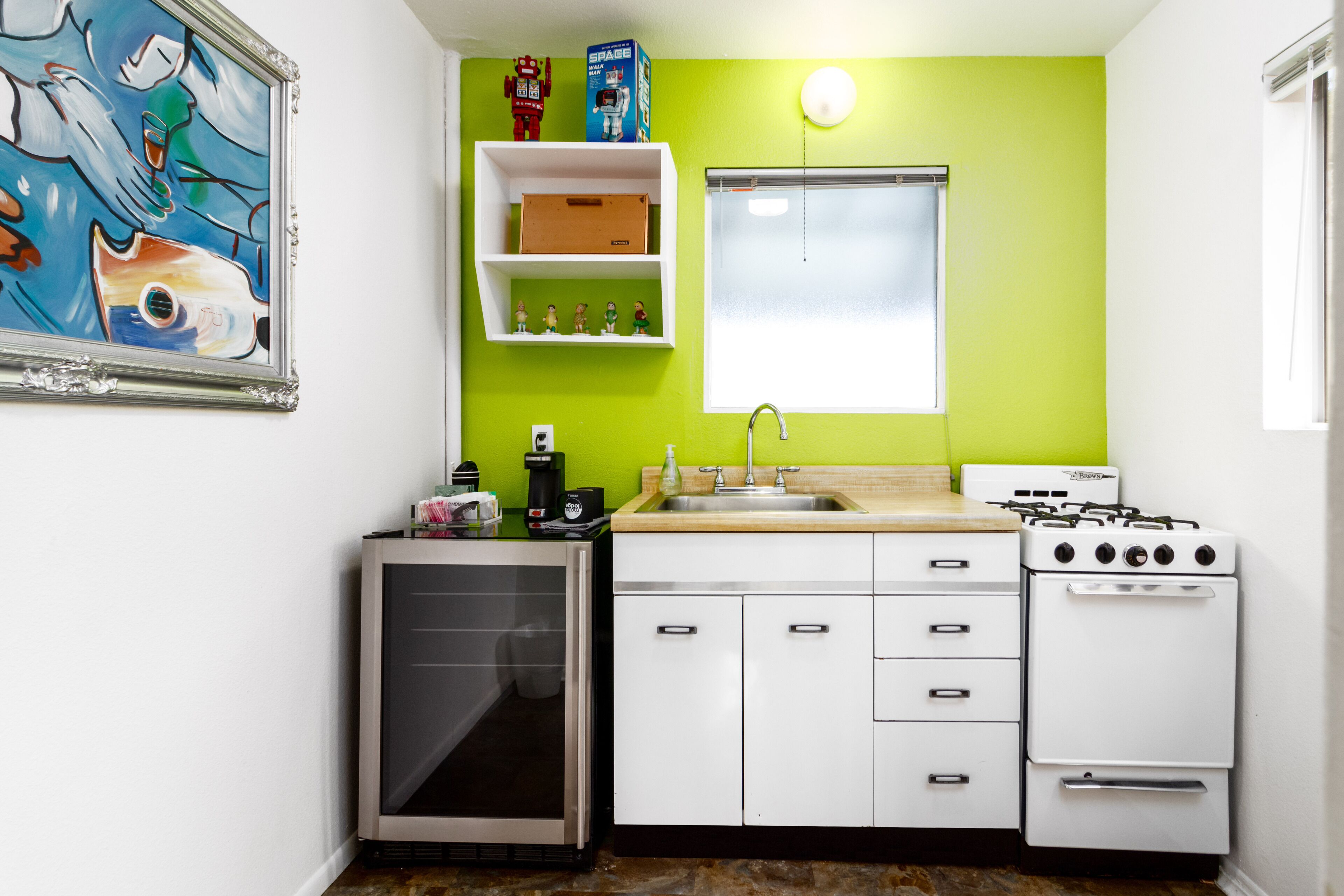 Una cocina compacta con armarios blancos, un fregadero, una estufa y un refrigerador.