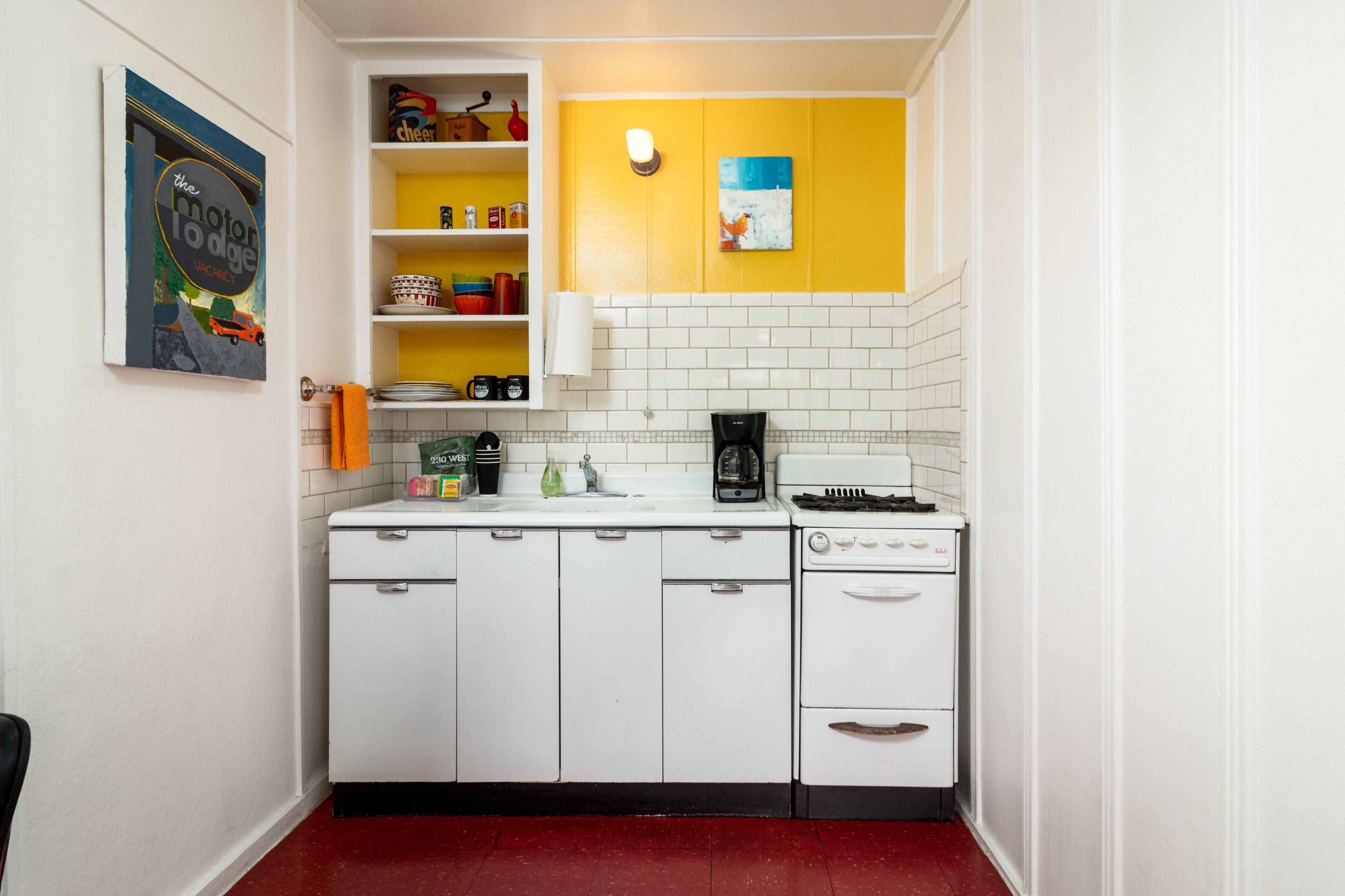 A compact kitchen with white cabinets, a white stove, and a yellow accent wall.
