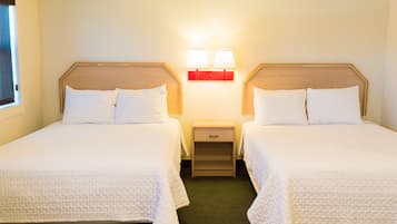 A hotel room with two beds, a nightstand with a lamp, and a window.