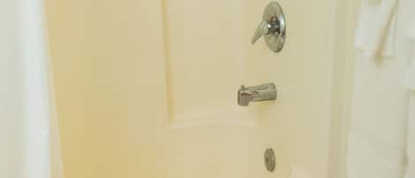 A bathroom with a bathtub, a towel rack, and a shower curtain.