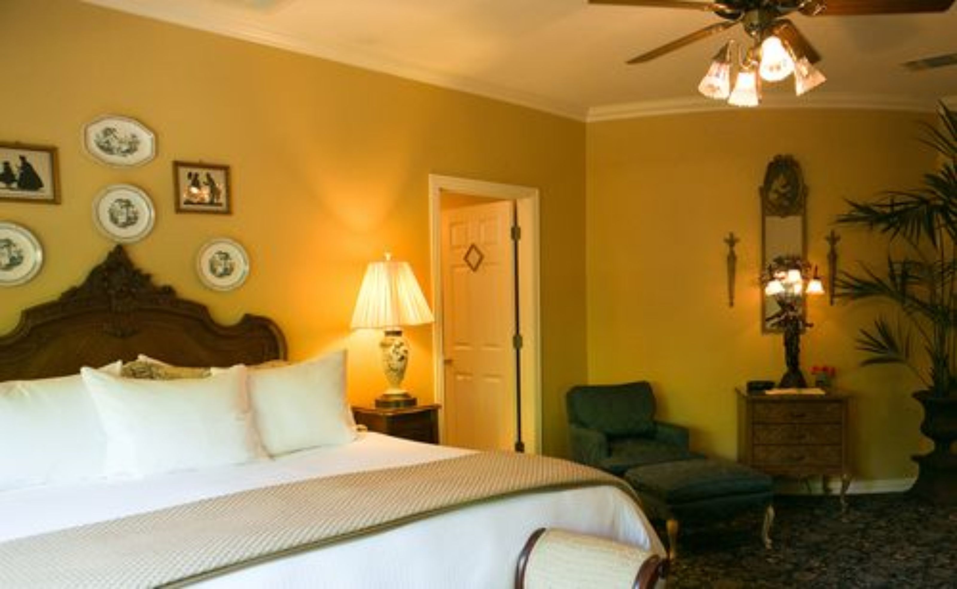 A hotel room with a bed, a chair, a nightstand, a lamp, and a ceiling fan.