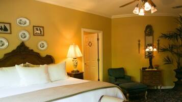 A hotel room with a bed, a chair, a nightstand, a lamp, and a ceiling fan.
