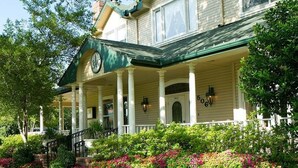 A two-story house with a porch, columns, and a clock.
