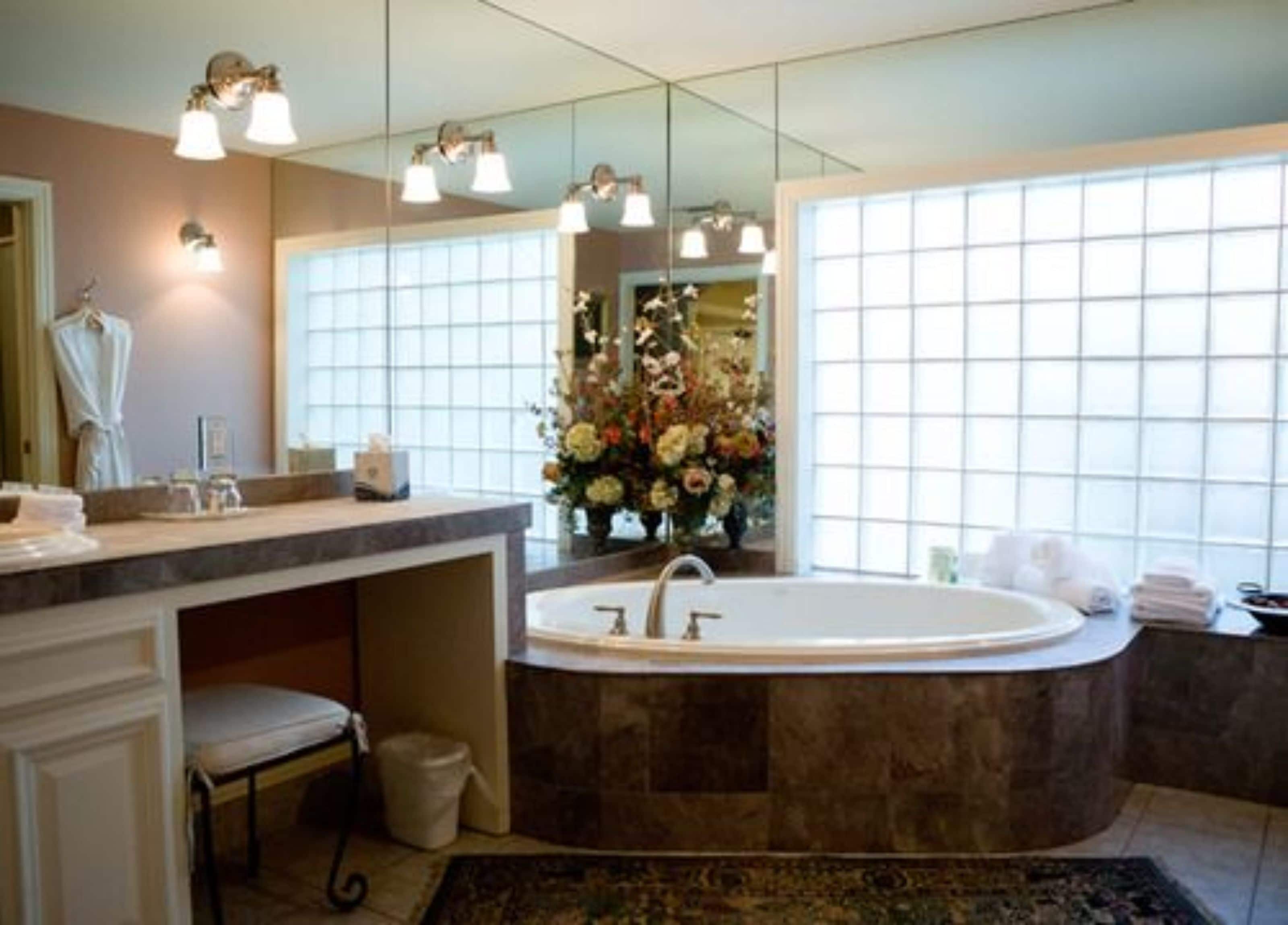 A bathroom with a freestanding bathtub, a vanity with a mirror, and a large window providing natural light.