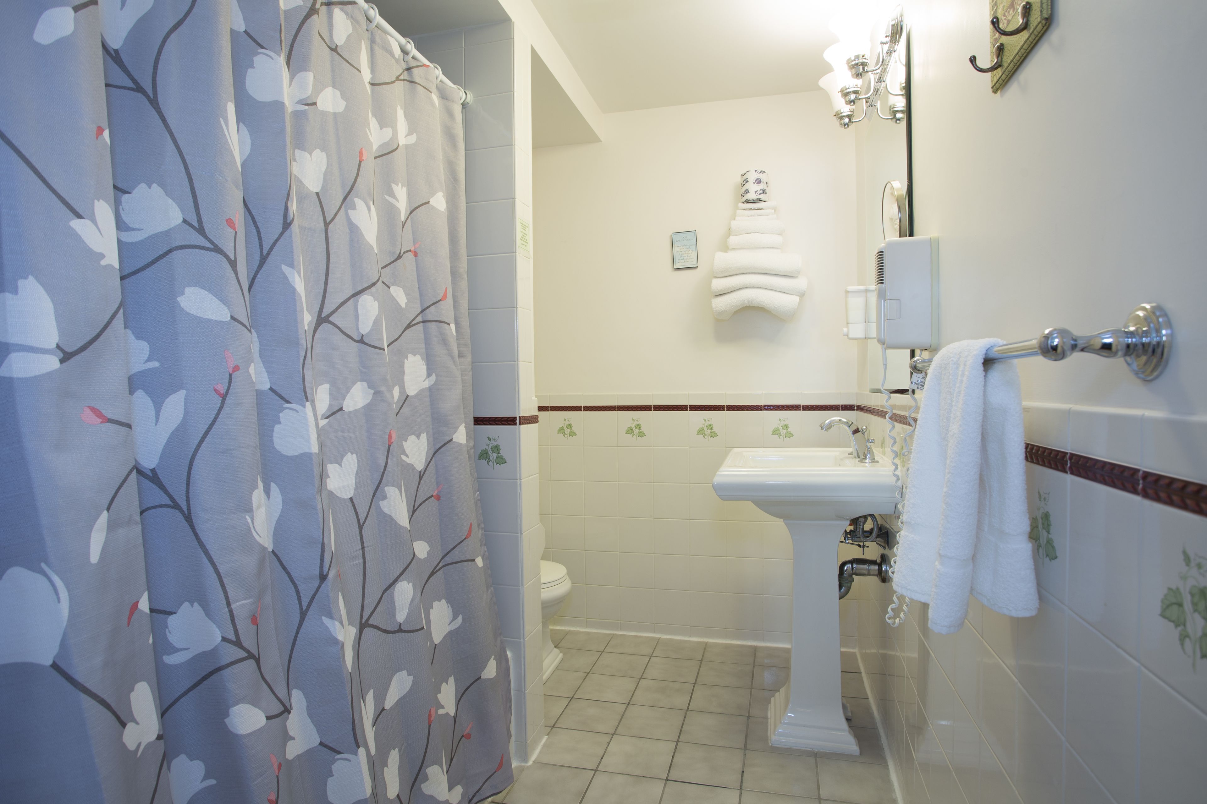 A bathroom with a shower curtain, a toilet, a sink, and a towel rack.