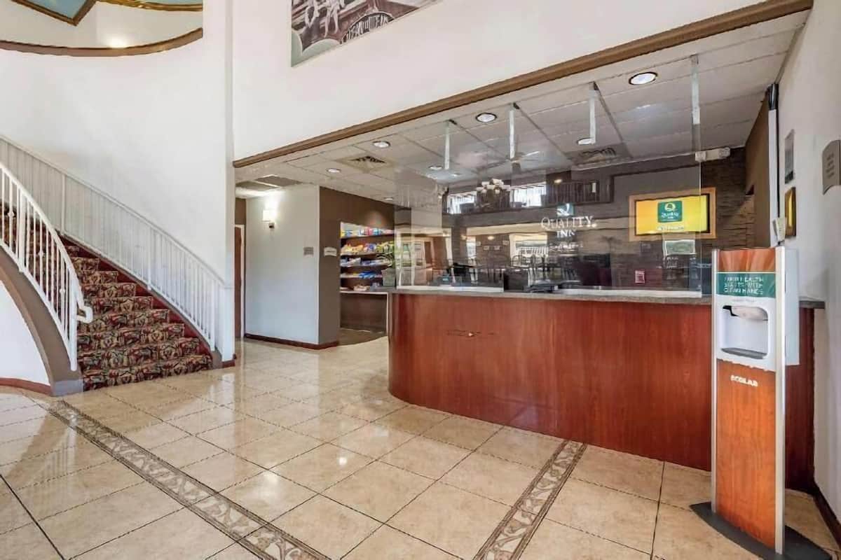 A hotel lobby with a reception desk, a staircase, and a coffee machine.