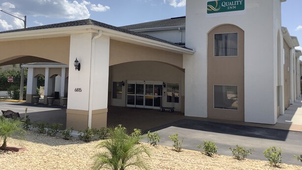 A Quality Inn with a white exterior, a covered entrance, and a signboard. - Quality Inn Zephyrhills-dade City (Zephyrhills)