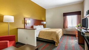 A hotel room with a bed, a desk, a chair, a TV, and a window with curtains. - Quality Inn Zephyrhills-dade City (Zephyrhills)