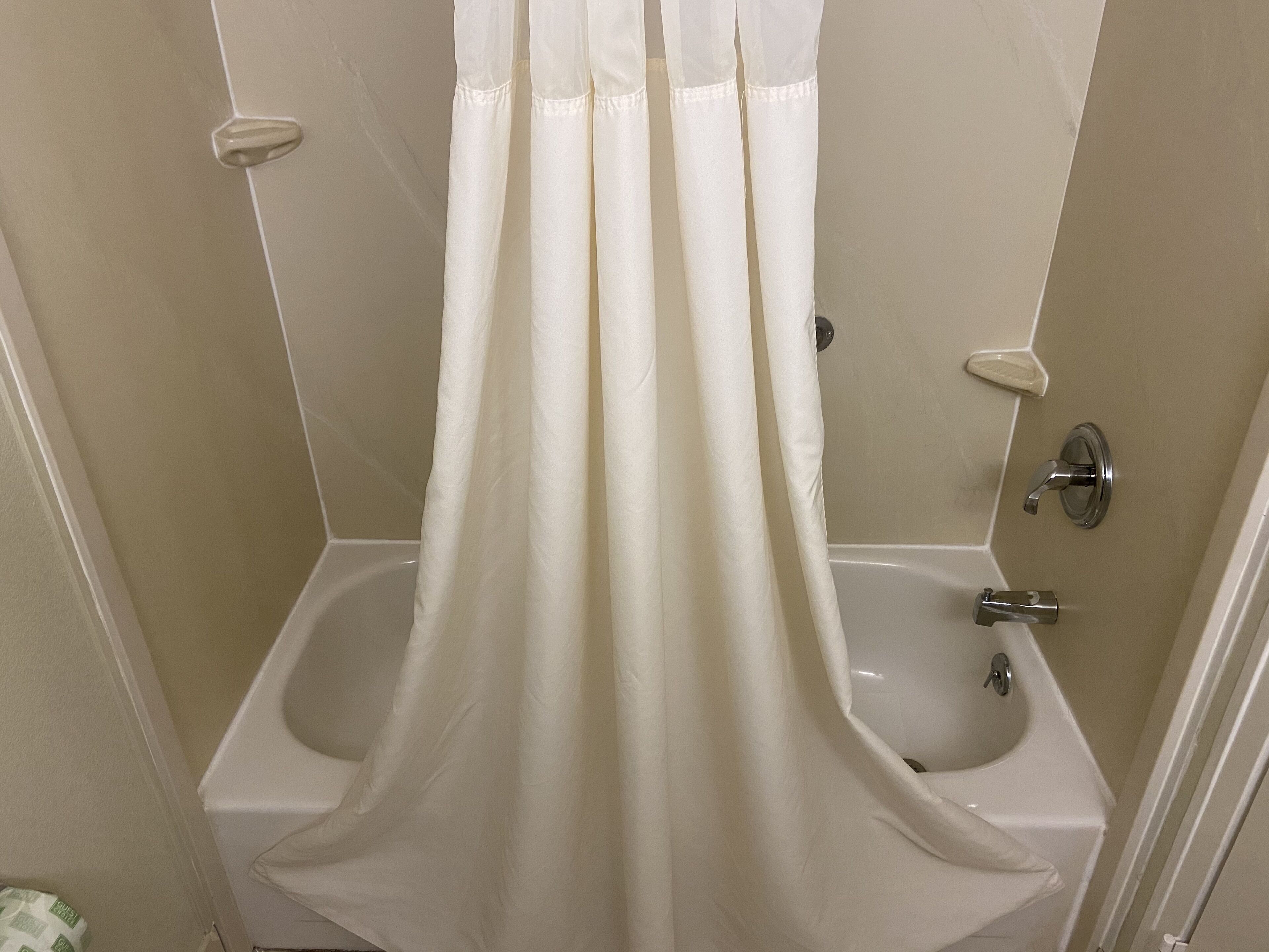Une salle de bain avec un rideau de douche, une baignoire et des toilettes.