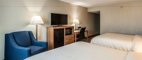 Habitación de hotel con dos camas, un escritorio, un televisor de pantalla plana, un sillón azul y dos lámparas de noche.