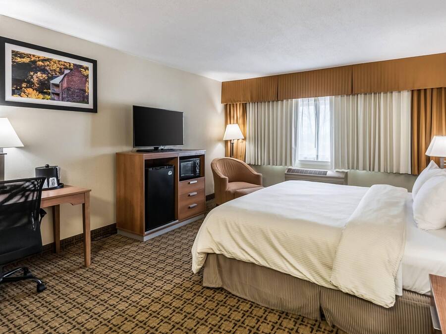 Una camera d'albergo con un letto grande, una scrivania con un computer, una TV e una sedia.