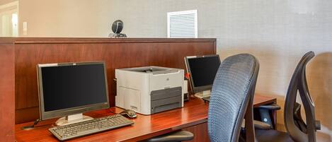 A cubicle with two monitors, a keyboard, a printer, and a chair.