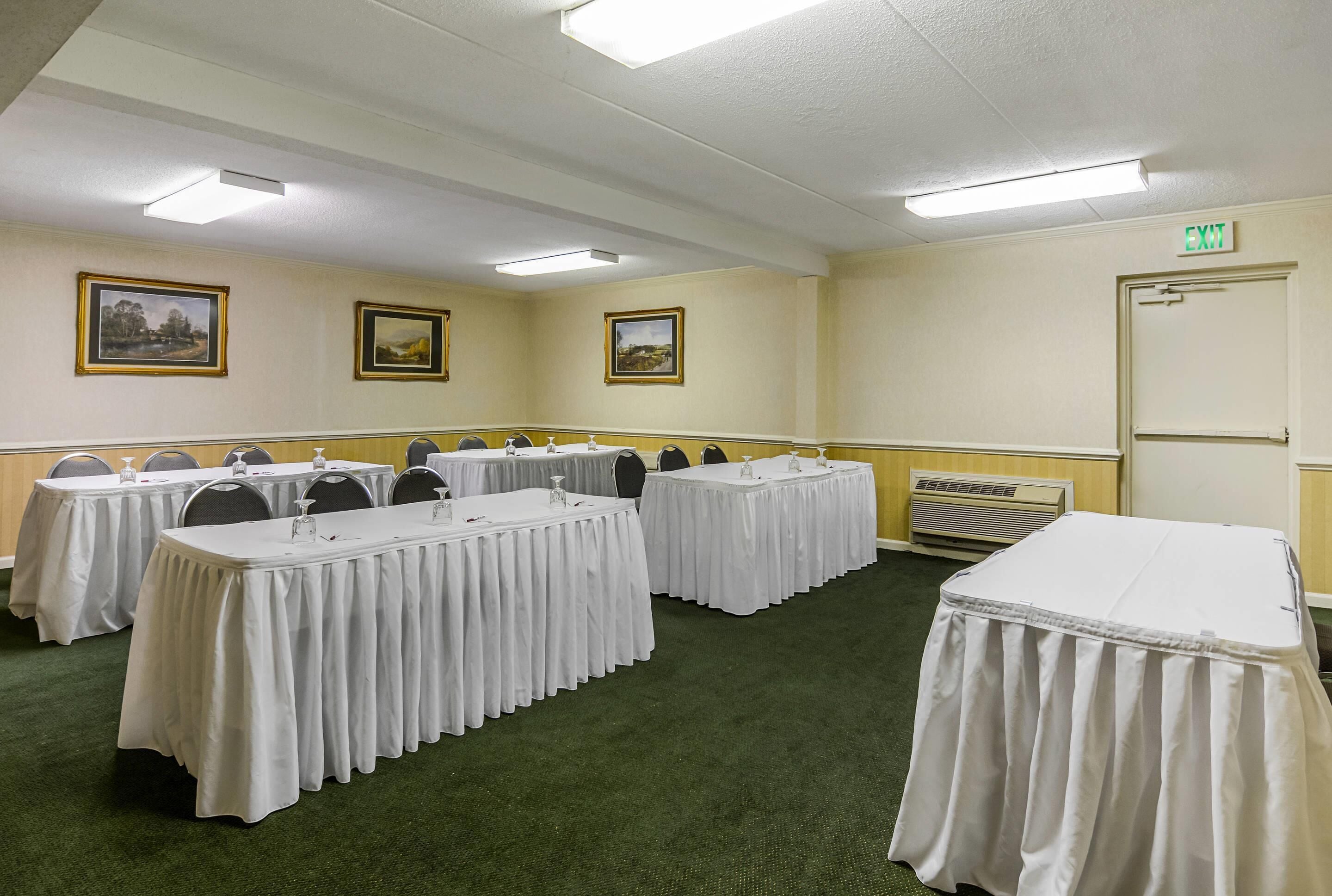 A conference room with multiple tables, chairs, and framed pictures on the walls.
