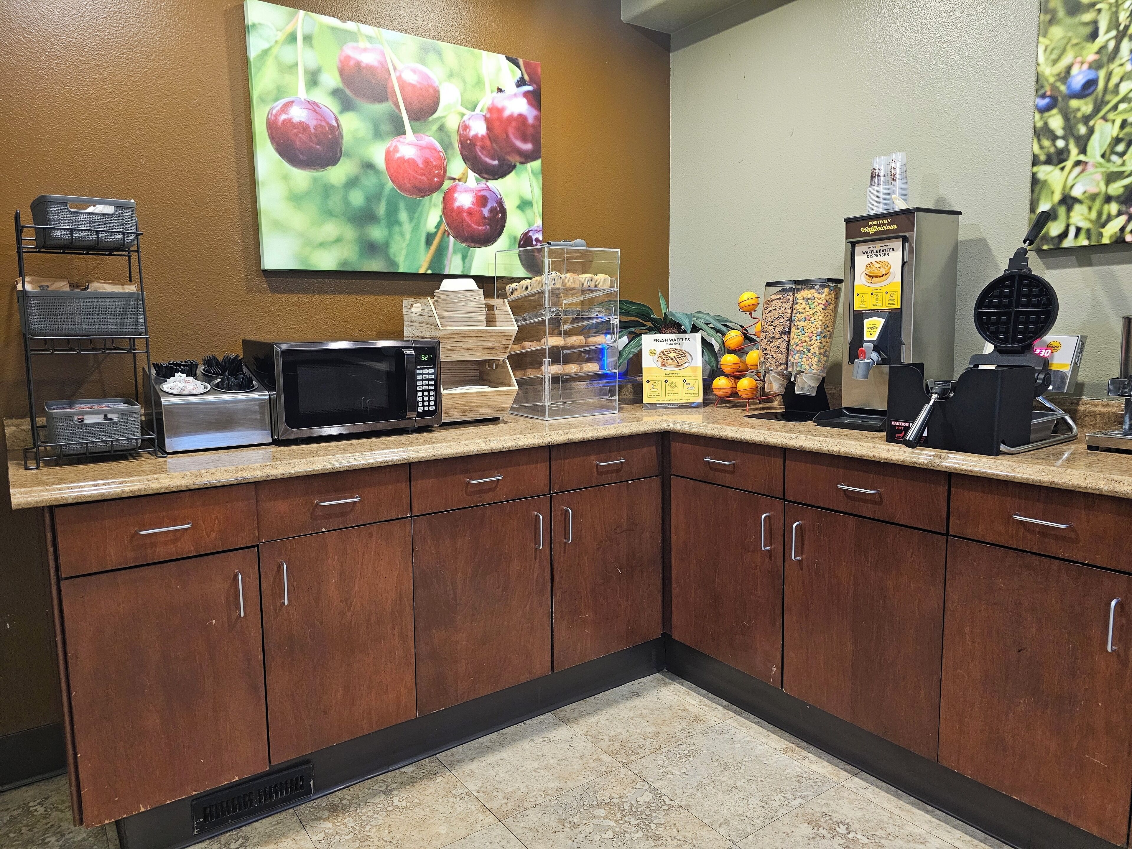 A breakfast bar with a microwave, waffle maker, and waffle station.