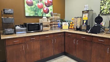 A breakfast bar with a microwave, waffle maker, and waffle station.