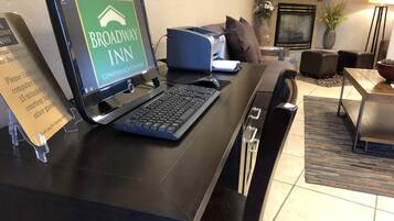 A reception desk with a computer displaying 'Broadway Inn Conference Center' and a sign advising to limit computer time to 15 minutes.