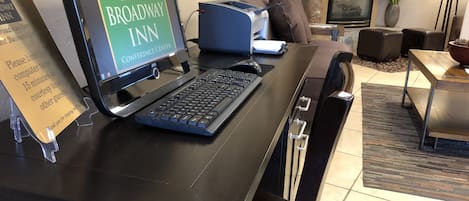Bancada de recepção com um computador exibindo 'Broadway Inn Conference Center' e um aviso para limitar o uso do computador a 15 minutos.