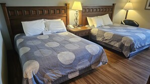 Two double beds with wooden headboards, bedside lamps, and a wooden floor.