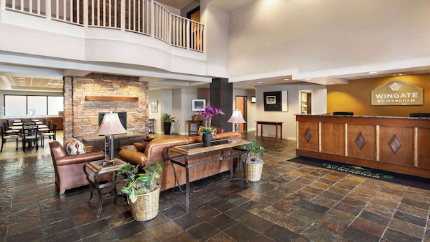 A spacious lobby with a leather sofa, a reception desk, and a stone fireplace. - Wingate by Wyndham Greenwood Village/Denver Tech (Greenwood Village)