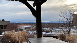 A wooden deck with a pergola overhead, a picnic table, and a view of a snowy landscape with mountains in the distance. - Wingate by Wyndham Greenwood Village/Denver Tech (Greenwood Village)