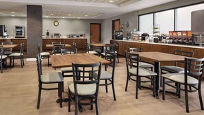 A spacious dining area with multiple tables and chairs, a coffee station, and a kitchen in the background. - Wingate by Wyndham Greenwood Village/Denver Tech (Greenwood Village)