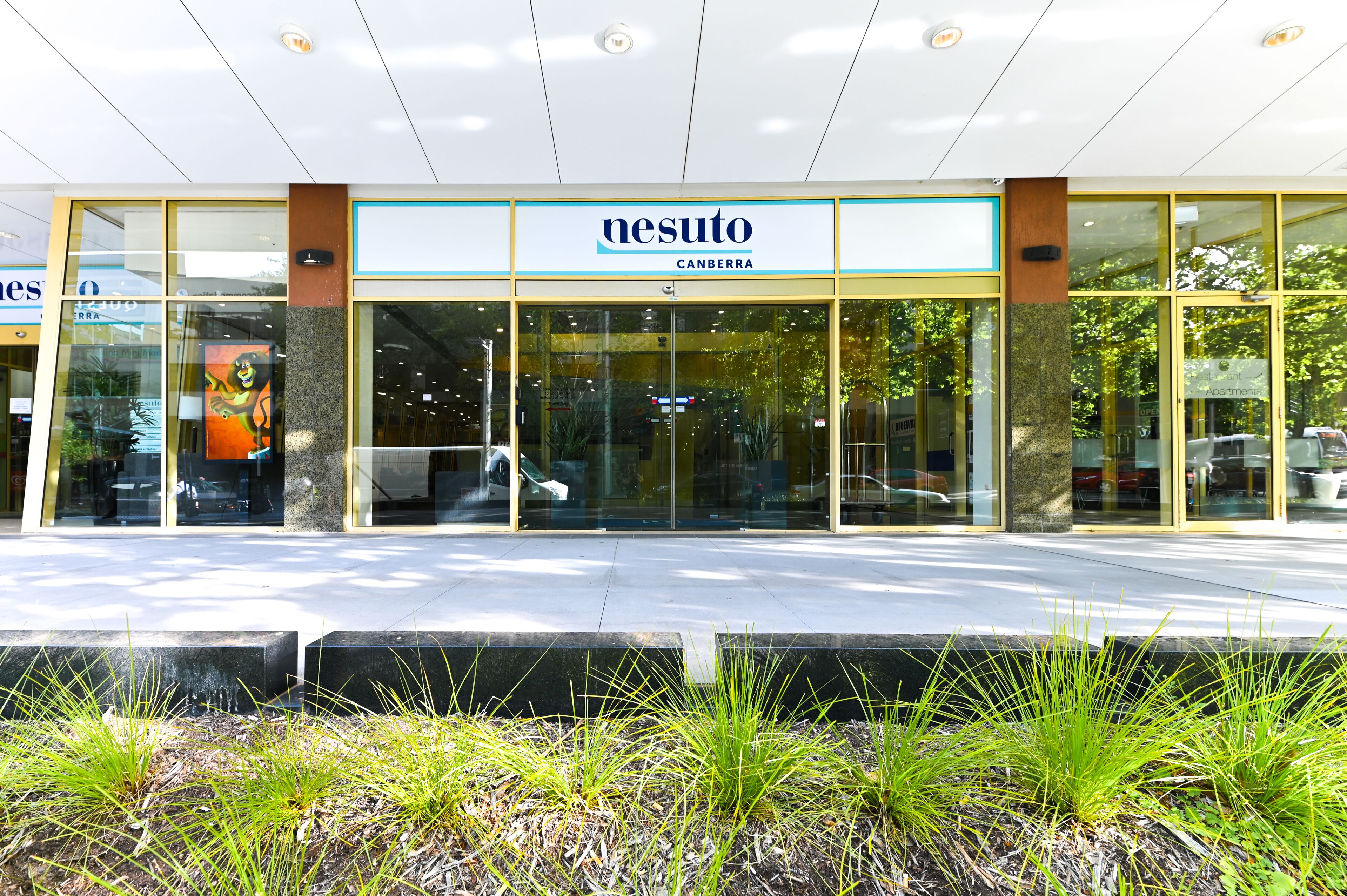 A modern building with a glass facade and a sign reading "nesuto Canberra."