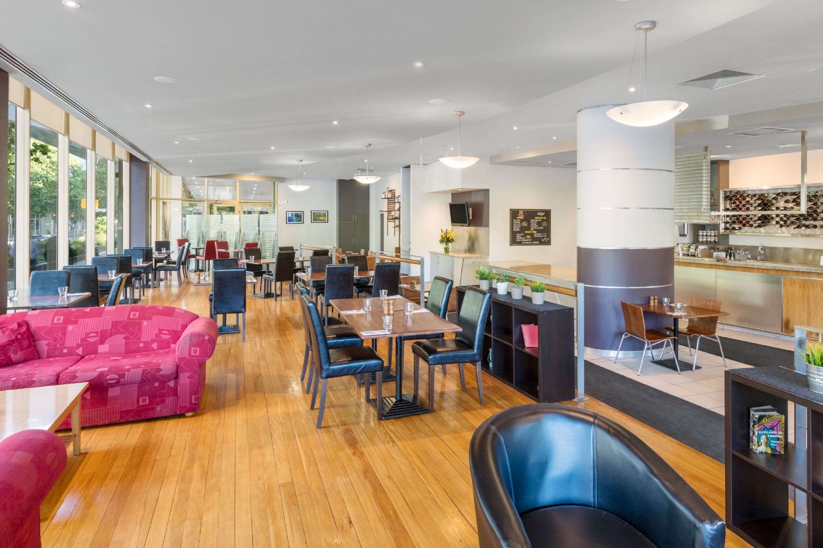 En rymlig restaurang med trägolv, flera sittområden med både bord och avskilda platser samt en bardisk med modern design.