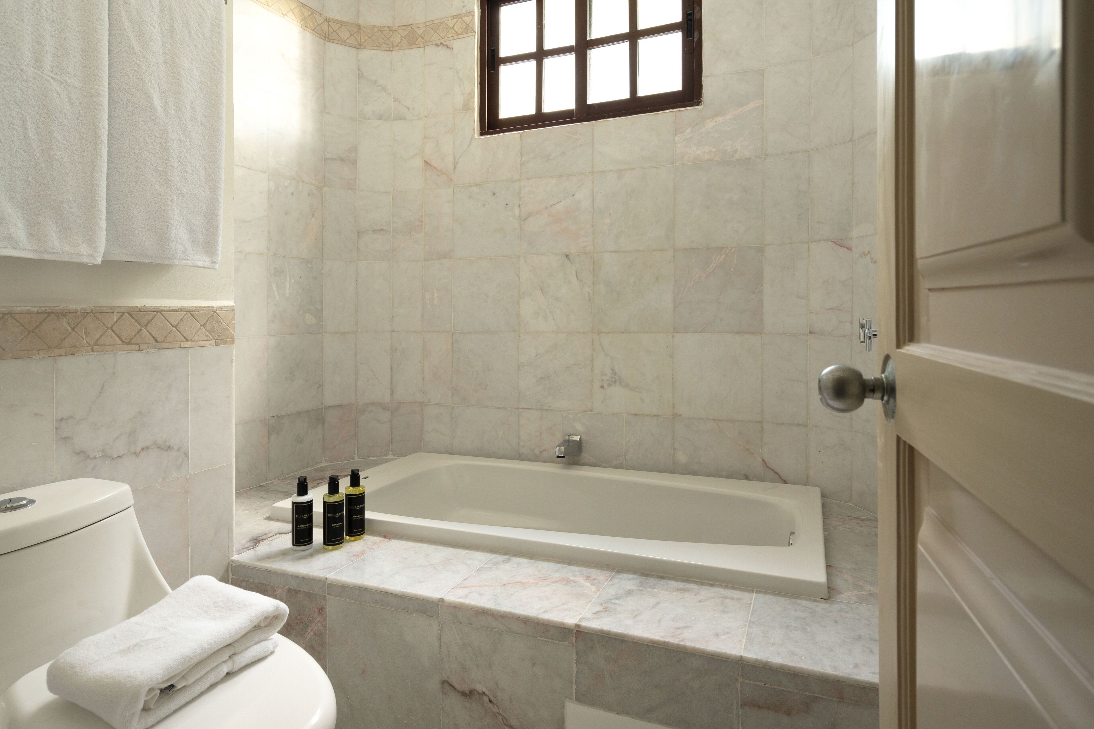 A bathroom with a bathtub, toilet, and a window.