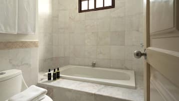 A bathroom with a bathtub, toilet, and a window.