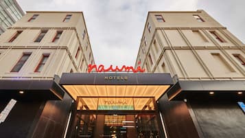 Entrada de un hotel con un letrero llamativo que dice "naumi HOTELS".
