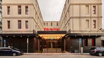 A hotel entrance with a modern facade, a prominent neon sign, and a clear view of the entrance area.