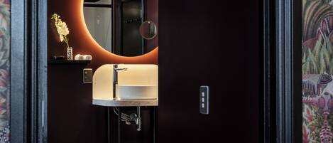 Un baño moderno con un espejo redondo, un lavabo blanco y un perchero para toallas.