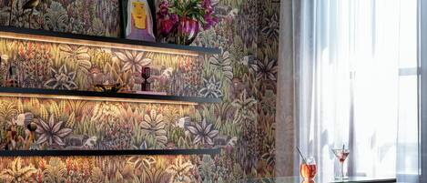 Eine Bar mit gemustertem Wandpapier, einer Leuchte und zwei Barhocker.