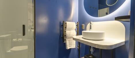 A modern bathroom with a blue wall, a white sink, and a glass shower enclosure.