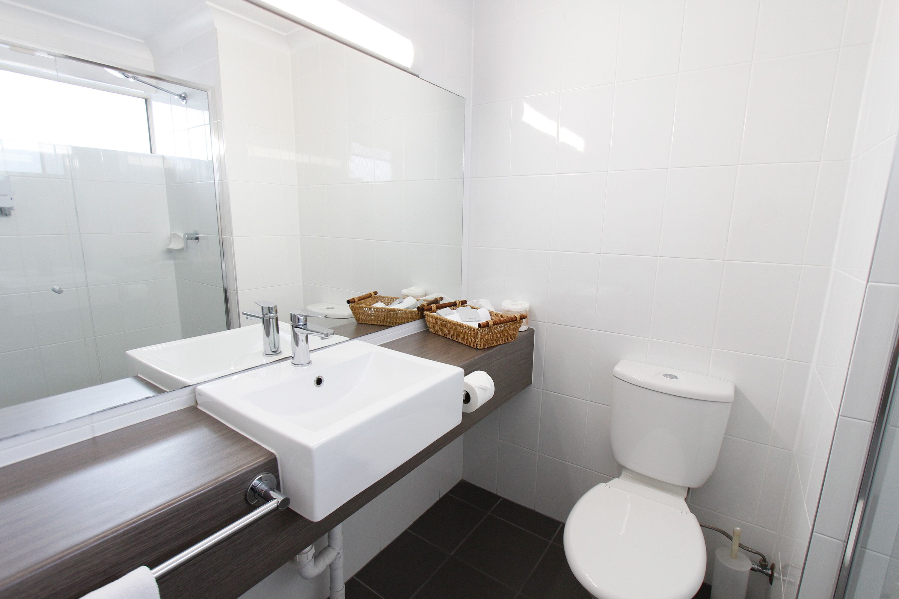 Ein modernes Badezimmer mit Duschkabine aus Glas, einem weißen Waschbecken und einer Toilette.
