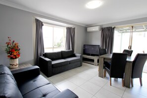 Relax in this stylish living room with a sofa, dining table, and flat-screen TV.