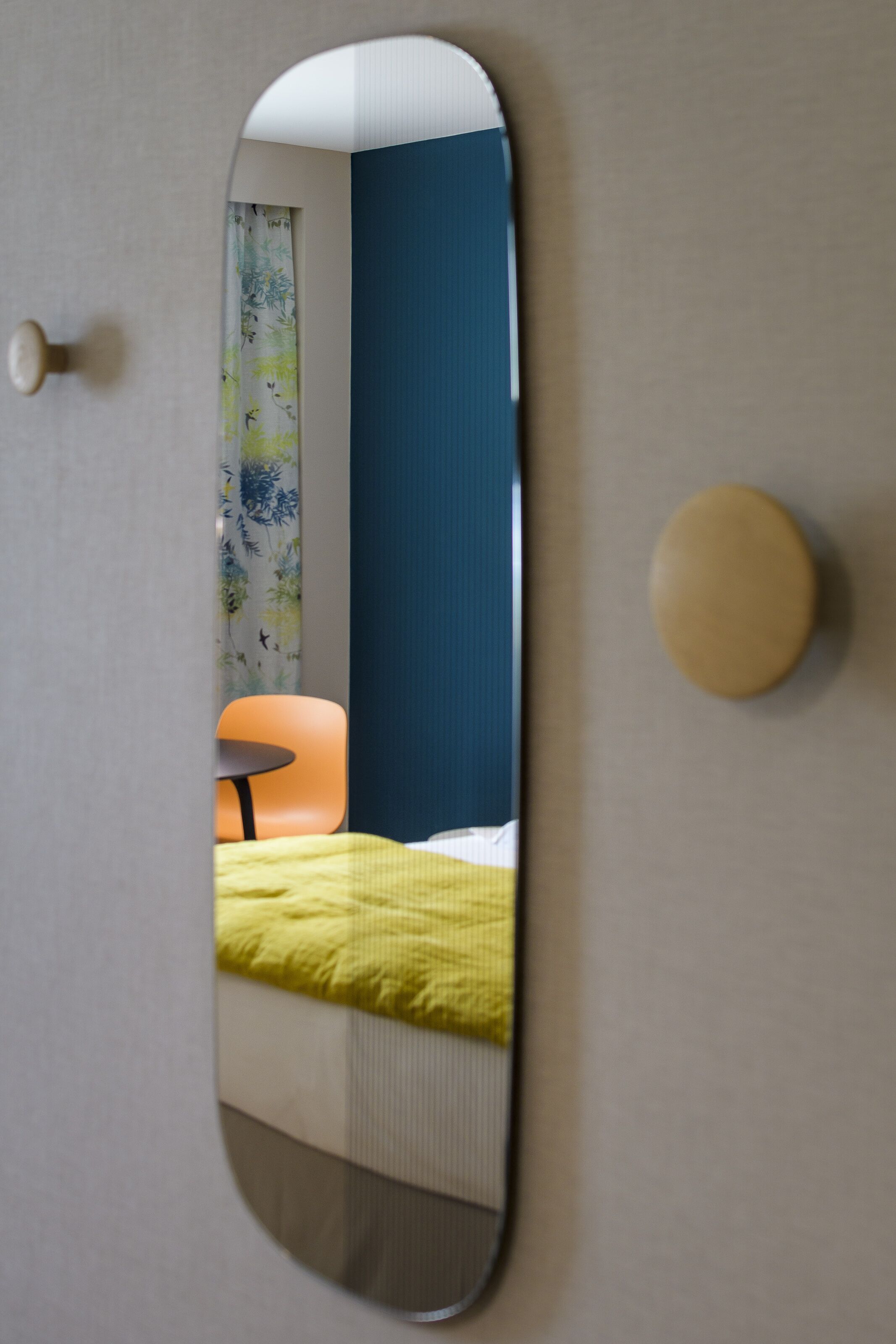 Een kamer met een bed, een stoel en een spiegel aan de muur.