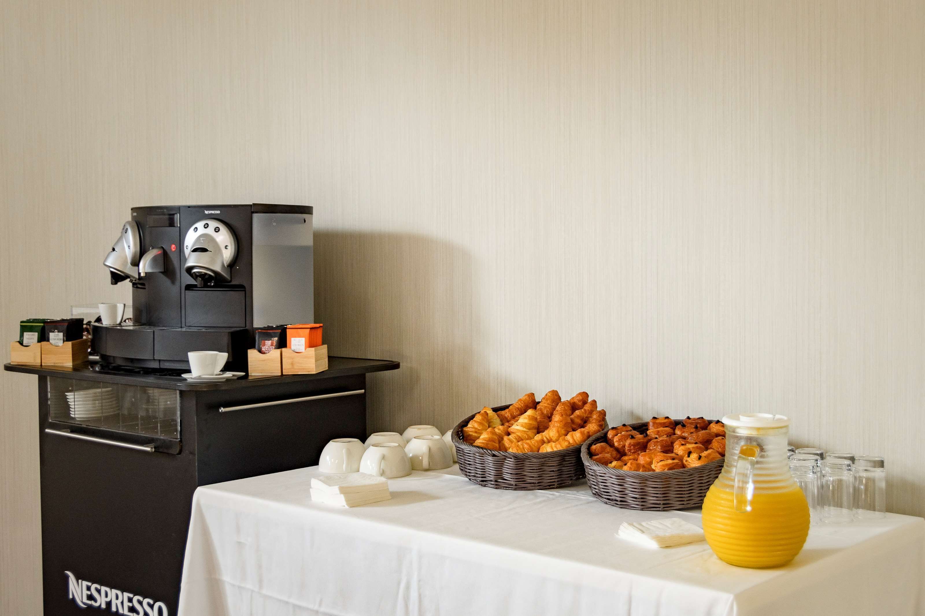 A breakfast setup with a coffee machine, croissants, and a jug of orange juice.