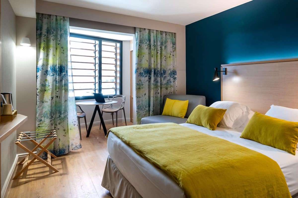 A hotel room with a bed, a desk, and a chair.