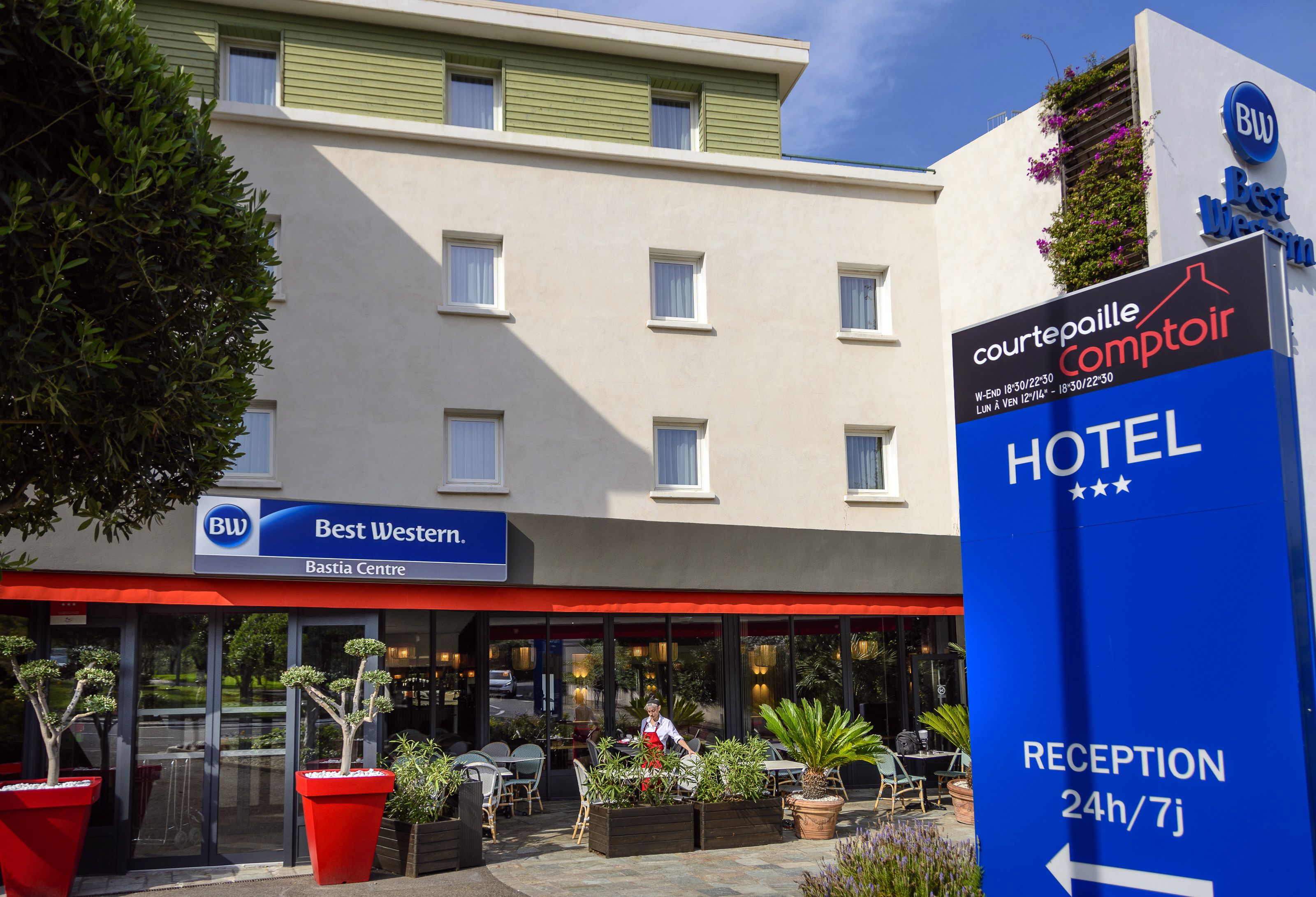 A hotel with a reception area, outdoor seating, and a Best Western sign.