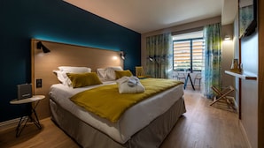A hotel room with a large bed, a small table, a chair, a window with curtains, and a view of the outside. - Best Western Montecristo (Bastia)