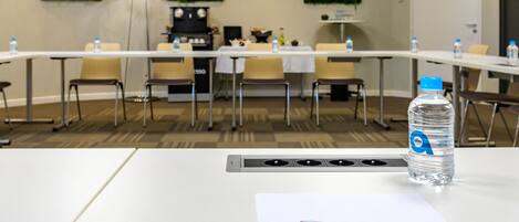 A conference room with a long table, chairs, a water bottle, and a pen on a table.