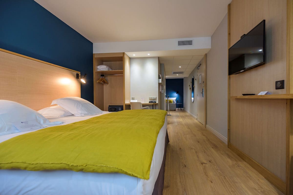 A hotel room with a bed, a television, and a desk with a chair.