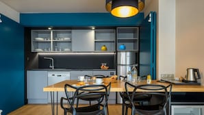 A modern kitchen with a wooden dining table, black chairs, and a built-in refrigerator. - Best Western Montecristo (Bastia)