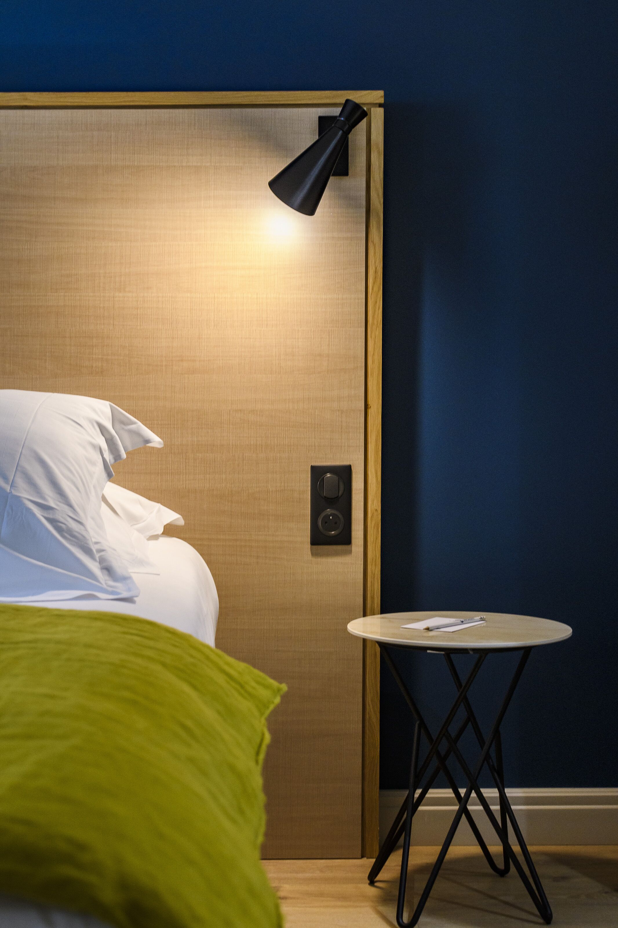 A room with a bed, a bedside table, and a lamp.