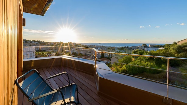 A balcony with a view of the sea and cityscape, featuring a chair and railing. - Best Western Montecristo (Bastia)