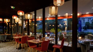 A restaurant with tables and chairs, large windows, and hanging lights. - Best Western Montecristo (Bastia)